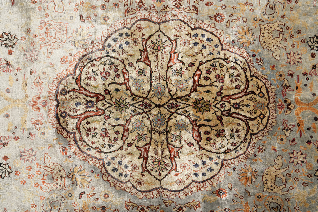 An antique Persian-style area rug with a faded central floral medallion, featuring a beige and dusty blue-gray base with rust red, brown, and navy accents.