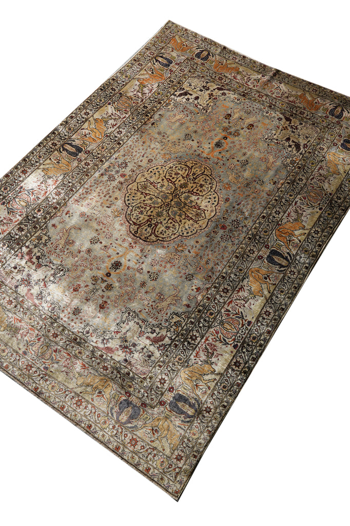 An antique-style Persian area rug with a distressed, faded design, featuring a central medallion and intricate floral motifs in muted beige, brown, gray, and rust orange tones, shown on a plain white background.