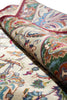 Load image into Gallery viewer, A close-up of a rolled area rug showing its detailed traditional pattern in cream, green, red, blue, and orange tones.