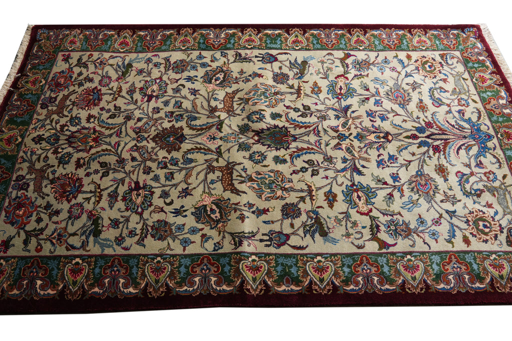 A rectangular Persian-style area rug with an intricate floral and vine pattern on a cream background, featuring a dark red border and teal accents.