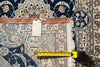 Load image into Gallery viewer, A close-up of an ornate patterned rug with cream, blue, and brown tones, showing a leather trim band, a blank tag, and a yellow tape measure laid across the fringe to indicate size.