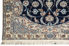 Load image into Gallery viewer, Close-up of an ornate area rug corner showing a dark navy field, cream border, and intricate floral motifs in blue, beige, and rust red with white fringe.