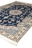 Load image into Gallery viewer, A traditional oriental area rug with a navy blue field, cream borders, and light blue accents, featuring intricate floral motifs and white fringe.