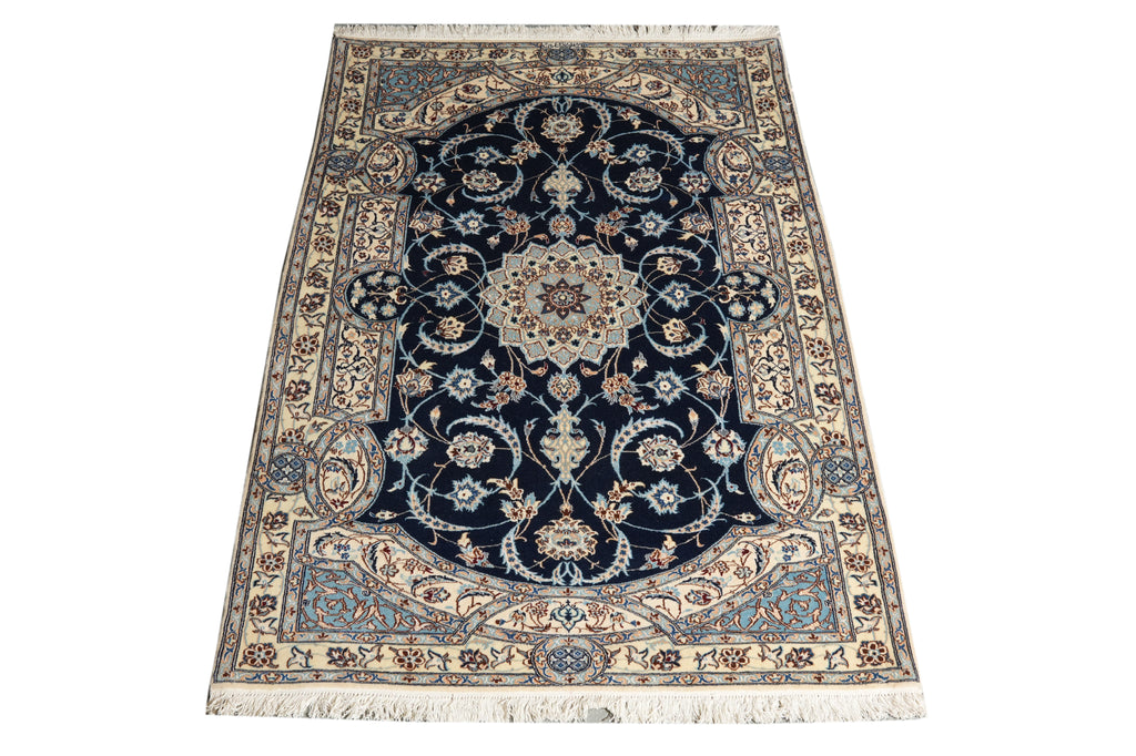 A traditional oriental-style area rug with a dark navy blue central field, intricate floral and vine motifs in beige, cream, and light blue, and a matching patterned border with white fringe on the top and bottom.