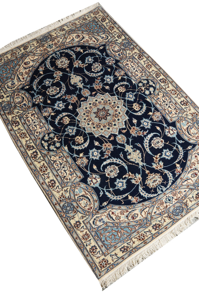 A traditional Persian-style area rug with a dark navy blue central field, intricate floral and vine motifs in beige, cream, and light blue, and a detailed border with cream fringe on the ends.