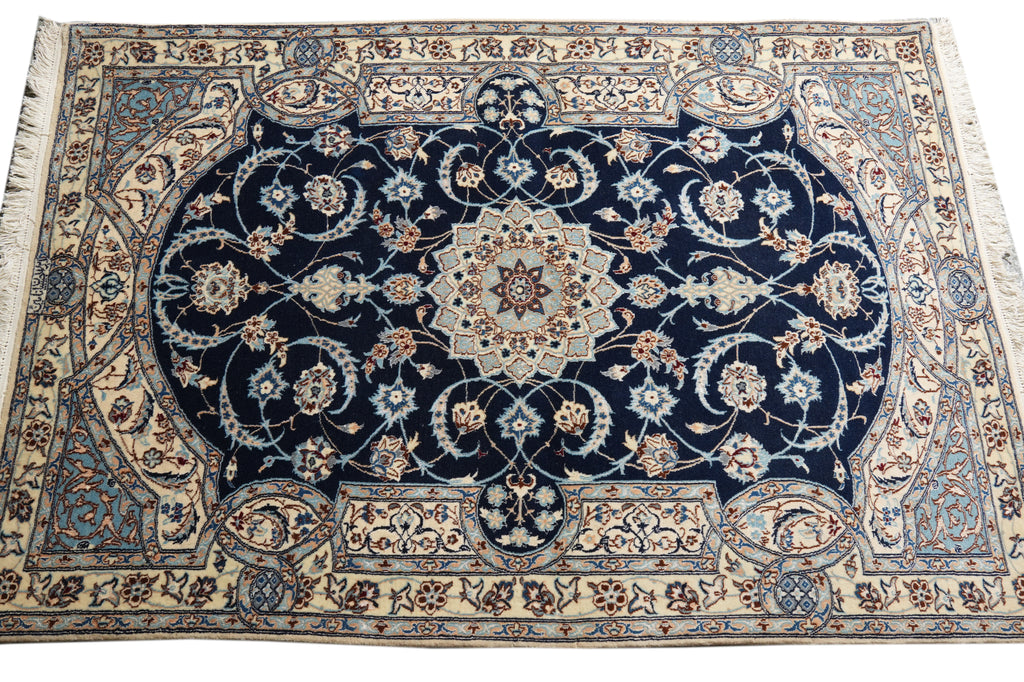 A traditional oriental area rug with a dark navy blue center field, cream borders, and intricate floral motifs in beige, light blue, and rust red.