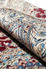 Load image into Gallery viewer, A close-up of a rolled area rug showing an intricate traditional pattern in beige, blue, red, and brown tones.