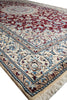 Load image into Gallery viewer, A close-up view of a traditional Persian-style area rug with a cream base, deep red central field, and blue and beige floral motifs, featuring a fringed edge.