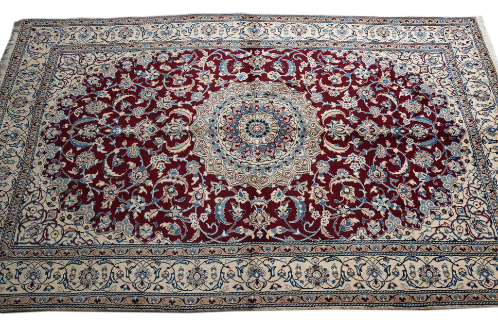 A traditional Persian-style area rug with a deep red central field, cream borders, and intricate blue and beige floral patterns.