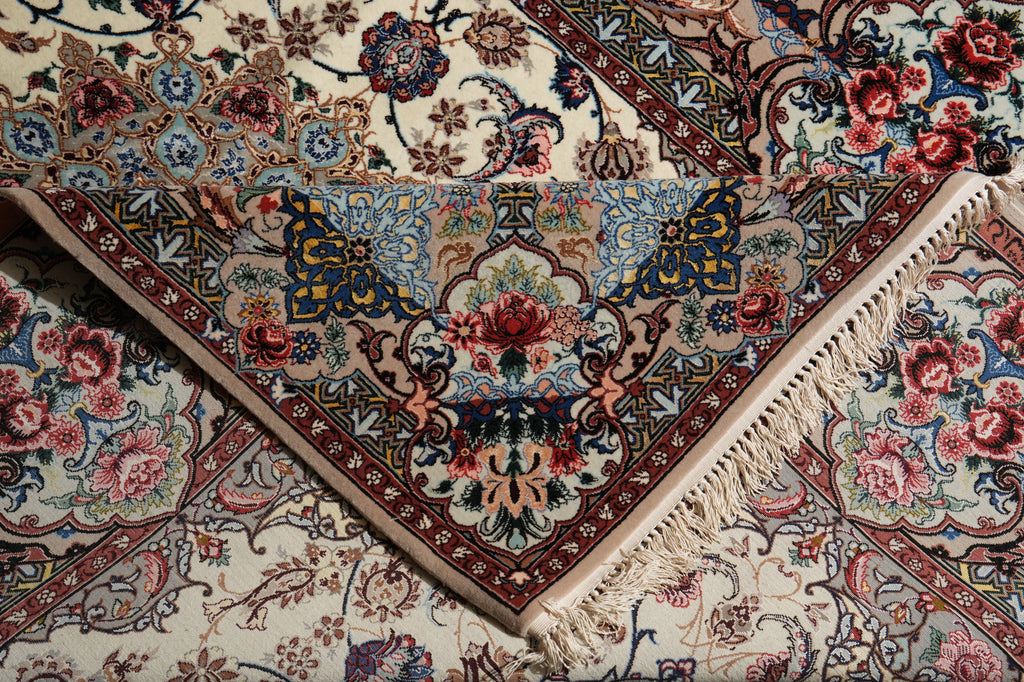 A close-up of a folded, triangular area rug with intricate floral and ornamental patterns in cream, blue, red, and brown, featuring white fringe along one edge.