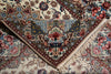 Load image into Gallery viewer, A close-up of a folded, triangular area rug with intricate floral and ornamental patterns in cream, blue, red, and brown, featuring white fringe along one edge.