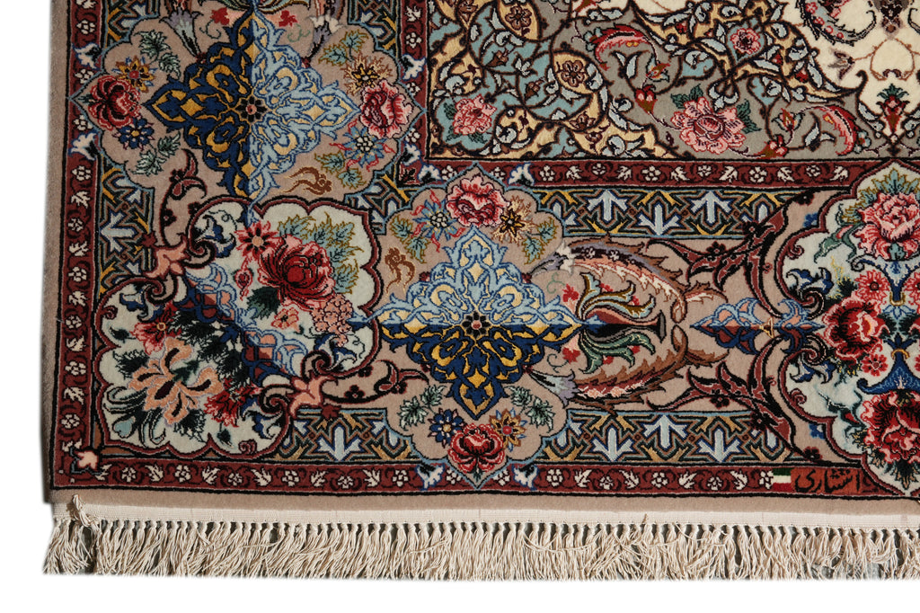 A close-up of an ornate Persian-style area rug showing its detailed floral and geometric patterns in beige, blue, red, and green, with cream-colored fringe at the bottom.