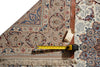 Load image into Gallery viewer, An ornate patterned area rug shown folded to display its design and fringed edge, with a yellow tape measure and paper tag placed along the bottom edge for scale.