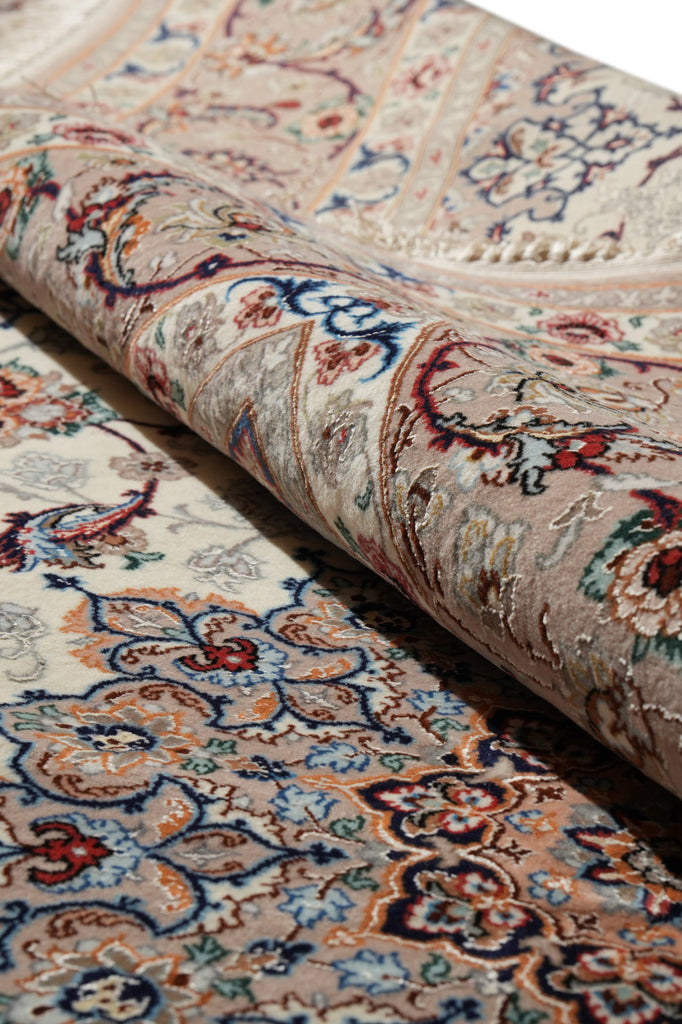 A close-up of a rolled area rug showing its detailed traditional floral and paisley pattern in beige, blue, red, and brown tones.