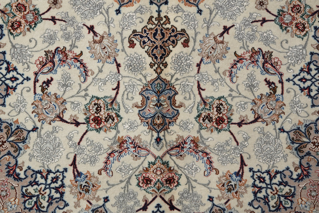 A close-up of an ornate traditional patterned rug with a central medallion and scrolling floral motifs in cream, blue, rust red, and gray.