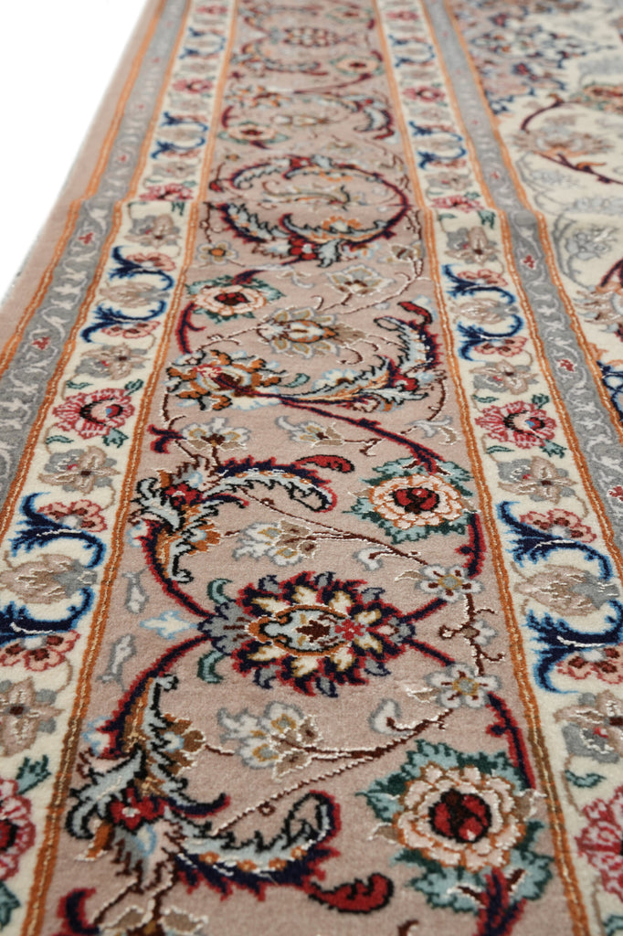 A close-up view of an ornate area rug with a traditional floral and scroll pattern in beige, red, blue, and gray tones.