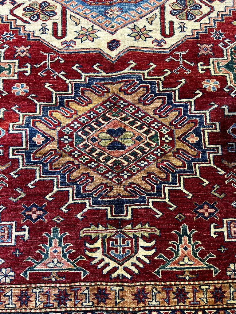 Detail of Super Kazak Rug Pattern and Color: "Close-up view of the detailed geometric pattern and rich red hues of a 6x9 Super Kazak rug, exemplifying traditional design."
