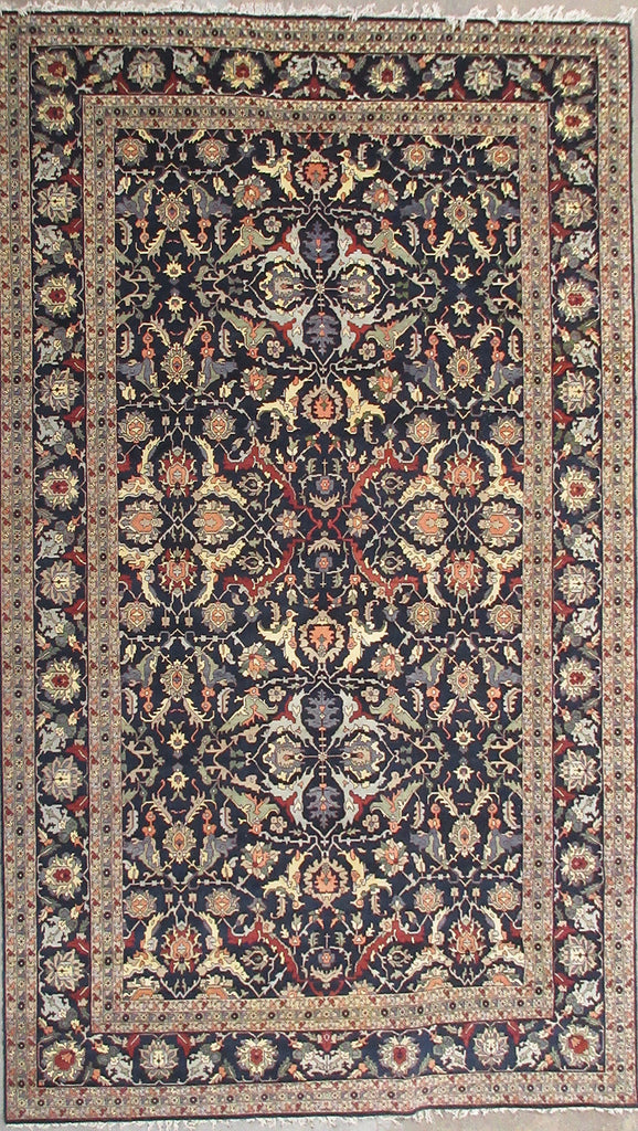 An ornate traditional oriental rug with a dark navy blue field, beige borders, and intricate floral motifs in red, gold, and cream.