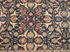 Load image into Gallery viewer, A close-up of an ornate traditional patterned rug with a dark navy blue background and intricate floral motifs in beige, red, orange, and muted green.