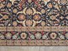 Load image into Gallery viewer, A close-up of an ornate traditional area rug with a dark navy blue field, featuring intricate floral and vine motifs in beige, red, and orange, with a detailed patterned border.
