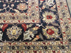 Load image into Gallery viewer, A close-up of a traditional patterned rug with a dark navy blue field, cream borders, and red, beige, and gray floral motifs.