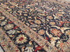Load image into Gallery viewer, A traditional Persian-style area rug with an intricate floral and vine pattern, featuring a dark navy blue field, beige borders, and accents of red, green, and orange.