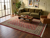 Load image into Gallery viewer, A large rectangular area rug with a red and beige geometric diamond pattern and fringe, styled in a modern living room.