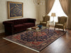 Load image into Gallery viewer, Living room with a dark red sofa, patterned rug, and ornate wall art.