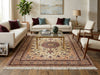 Load image into Gallery viewer, A large traditional area rug with a beige, red, and blue floral medallion pattern, styled in a mid-century modern living room with cream sofas, wooden chairs, and a glass-top coffee table.