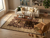 Load image into Gallery viewer, A styled living room scene featuring a large rectangular area rug with a brown and beige floral pattern, placed under a wooden coffee table. The room includes a cream sofa with decorative pillows, a tan armchair, a small gold side table, a floor lamp, and a potted plant.