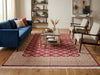 Load image into Gallery viewer, A large rectangular area rug with a red and beige geometric pattern and fringe, styled in a bright living room.
