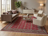 Load image into Gallery viewer, A large traditional-style area rug with a red, beige, and gray pattern is shown in a staged living room setting with a brown sofa, two cream armchairs, a glass coffee table, and a sideboard.