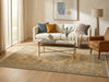 Load image into Gallery viewer, A styled living room scene featuring a large beige and blue traditional-style area rug on a light wood floor, with a white sofa, glass coffee table, and tan armchair in a sunlit interior.