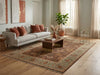 Load image into Gallery viewer, A large traditional-style area rug in earthy brown, beige, and muted blue tones, styled in a modern living room with a gray sofa, wooden coffee table, and light wood floors.