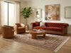 Load image into Gallery viewer, A styled living room featuring a rust-red tufted sofa, a tan leather armchair, a wooden coffee table, and a large patterned area rug on a light wood floor.
