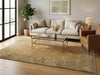 Load image into Gallery viewer, A large traditional-style area rug in beige, gold, and muted green tones is styled in a bright, modern living room with a light beige sofa, a glass-top coffee table, and a brown leather armchair.