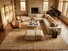 Load image into Gallery viewer, A large beige patterned area rug in a bright, modern living room with a cream sectional sofa, leather armchairs, a white coffee table, and a fireplace in the background.