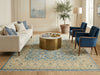 Load image into Gallery viewer, Living room with a beige sofa, blue chairs, and a gold coffee table on a patterned rug.