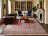 Load image into Gallery viewer, A large traditional oriental area rug with a red, beige, and blue geometric pattern, styled in a classic living room with a dark brown leather Chesterfield sofa, blue armchairs, and a wooden coffee table.