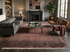 Load image into Gallery viewer, A large traditional oriental area rug in muted red, brown, and beige tones, styled in a cozy living room with a dark gray leather Chesterfield sofa, a dark wood coffee table, and two mid-century modern armchairs.