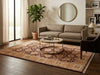 Load image into Gallery viewer, A traditional-style area rug with an intricate floral pattern in beige, rust, and brown tones, styled in a modern living room setting with a gray sofa, round coffee table, and potted plant.